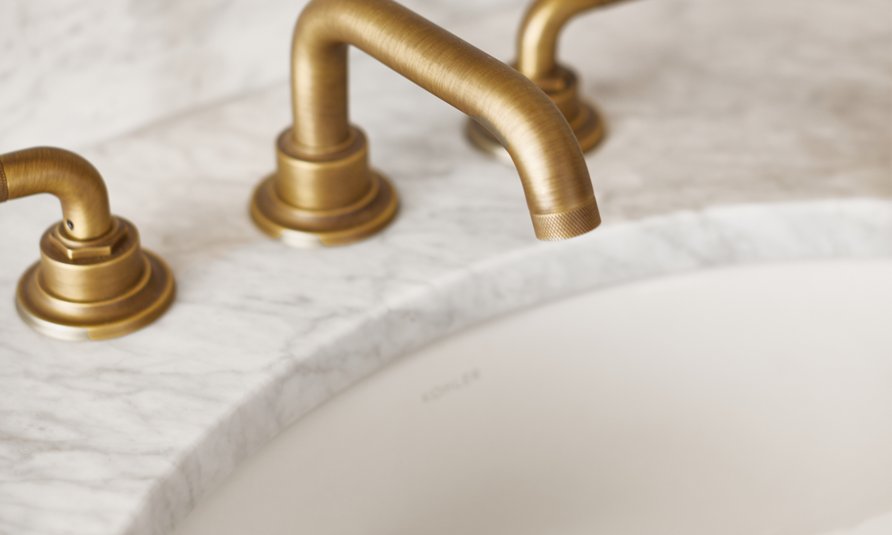 Closeup of marble countertop and satin brass faucet