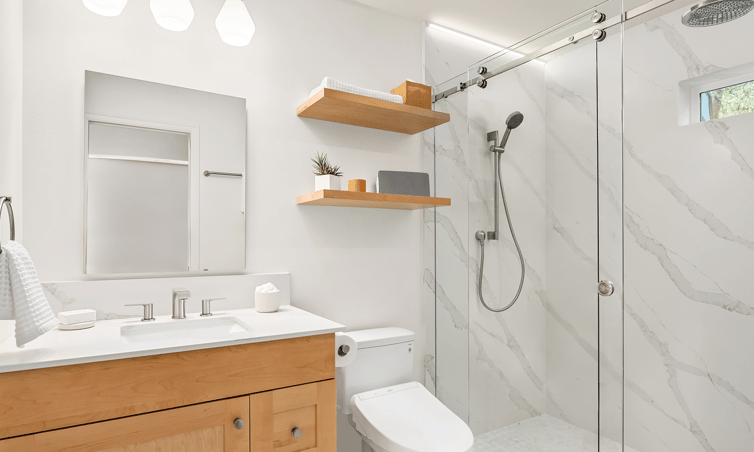 Modern white bathroom with frameless glass shower and slab walls and maple vanity